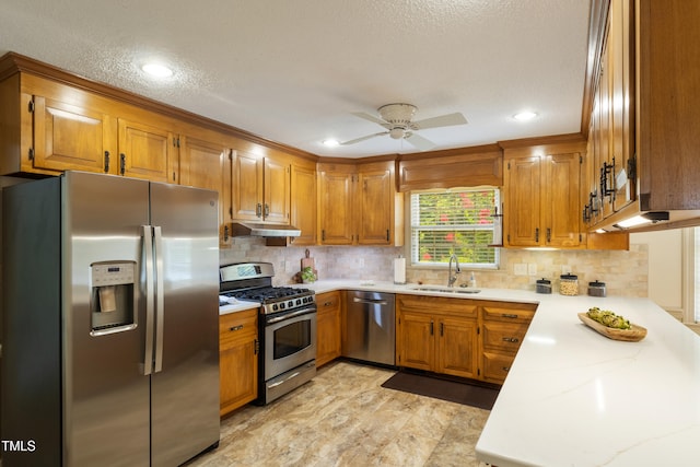 4009 Pepperton Dr, Raleigh, NC 27606 - kitchen featuring stainless steel appliances, under cabinet range hood, brown cabinets, tasteful backsplash, and a textured ceiling