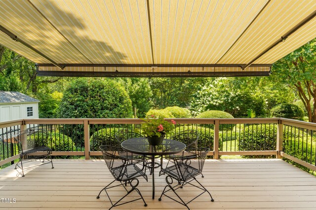 4009 Pepperton Dr, Raleigh, NC 27606 - deck with an outdoor structure, outdoor dining area, and view of wooded area
