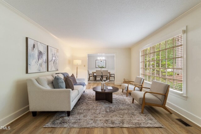 4009 Pepperton Dr, Raleigh, NC 27606 - living room featuring a chandelier, healthy amount of natural light, crown molding, and wood finished floors