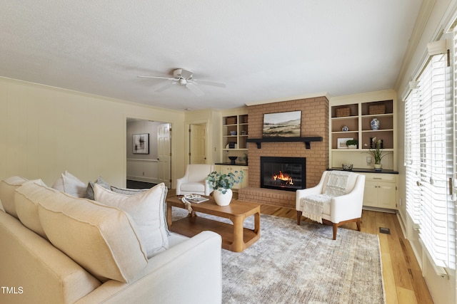 4009 Pepperton Dr, Raleigh, NC 27606 - living area featuring a fireplace, ceiling fan, built in features, and light wood finished floors
