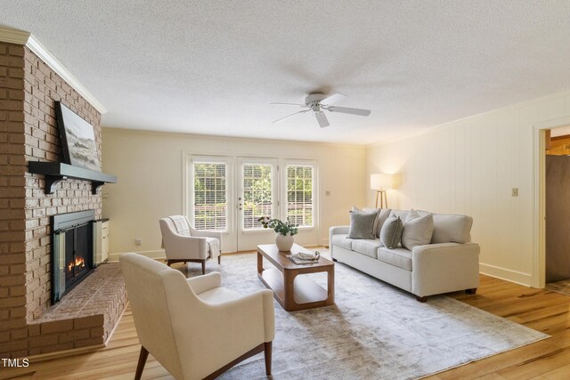 4009 Pepperton Dr, Raleigh, NC 27606 - living area with ceiling fan, a brick fireplace, light wood-type flooring, a textured ceiling, and ornamental molding