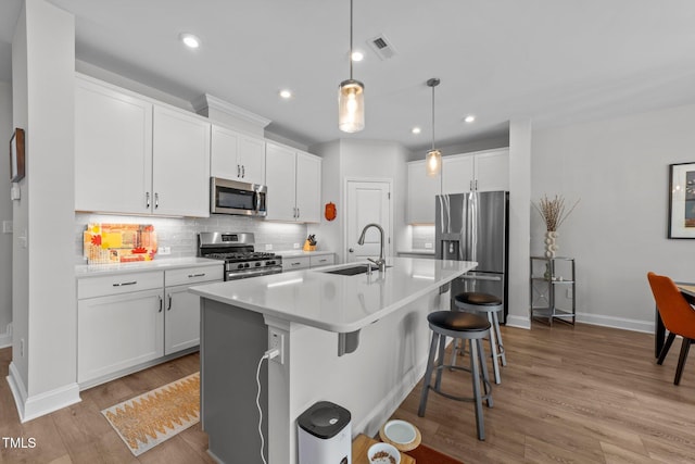 1315 Canary Pepper Dr Unit 28, Durham, NC 27713 - kitchen featuring stainless steel appliances, light wood-type flooring, tasteful backsplash, white cabinets, and a breakfast bar