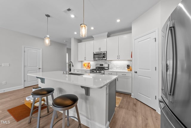 1315 Canary Pepper Dr Unit 28, Durham, NC 27713 - kitchen with appliances with stainless steel finishes, tasteful backsplash, a kitchen breakfast bar, white cabinets, and light wood-style floors