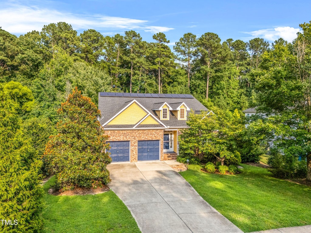 308 Harkness Cir, Durham, NC 27705 - view of front facade with a front yard, concrete driveway, a garage, and roof mounted solar panels