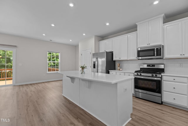1119 Platform Dr, Apex, NC 27502 - kitchen featuring appliances with stainless steel finishes, a kitchen island, backsplash, light countertops, and white cabinets