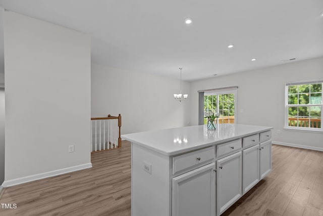 1119 Platform Dr, Apex, NC 27502 - kitchen with light wood finished floors, a kitchen island, white cabinets, light countertops, and recessed lighting