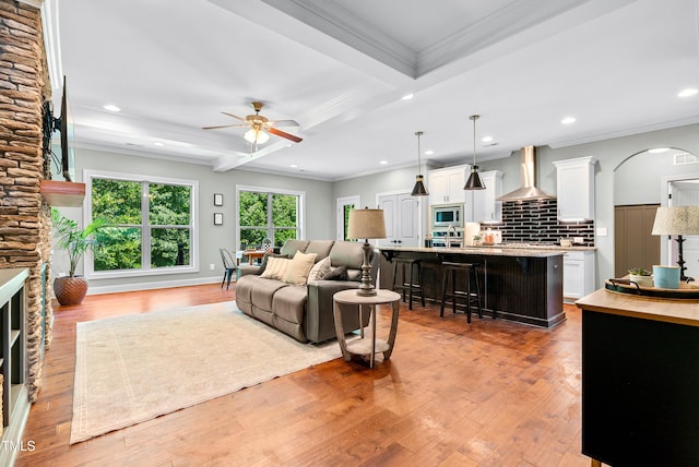 3313 Bentwinds Bluffs Ln, Fuquay Varina, NC 27526 - living room with ceiling fan, light wood-style flooring, a stone fireplace, ornamental molding, and recessed lighting