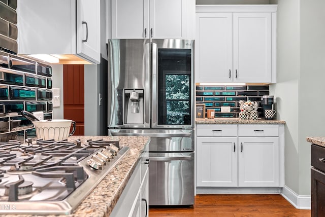 3313 Bentwinds Bluffs Ln, Fuquay Varina, NC 27526 - kitchen featuring appliances with stainless steel finishes, tasteful backsplash, white cabinetry, wood finished floors, and light stone counters