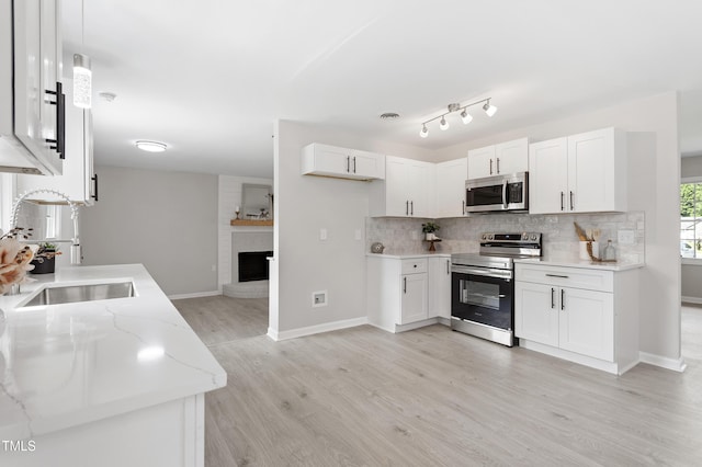 946 Jacksontown Rd, Henderson, NC 27537 - kitchen with appliances with stainless steel finishes, light wood-style floors, decorative backsplash, light stone countertops, and white cabinets