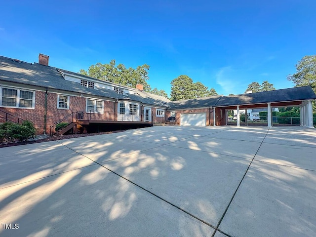 141 Country Club Dr, Henderson, NC 27536 - view of front of property with an attached garage, a chimney, concrete driveway, a deck, and brick siding