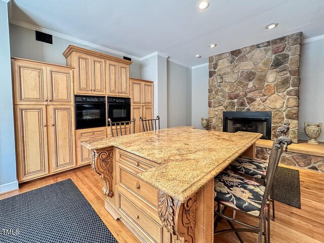 141 Country Club Dr, Henderson, NC 27536 - kitchen featuring light wood-style flooring, light stone counters, a breakfast bar, crown molding, and a center island