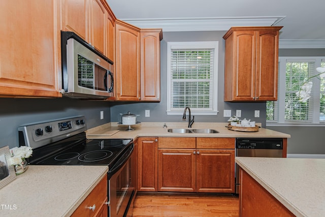 301 Grove Hall Ln, Mebane, NC 27302 - kitchen featuring stainless steel appliances, crown molding, light countertops, light wood-style flooring, and brown cabinetry