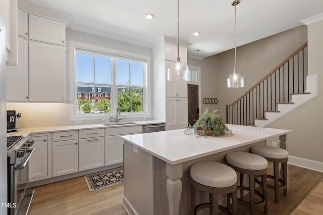 930 Watercolor Way, Durham, NC 27713 - kitchen featuring stainless steel appliances, light wood-style floors, a center island, white cabinetry, and ornamental molding