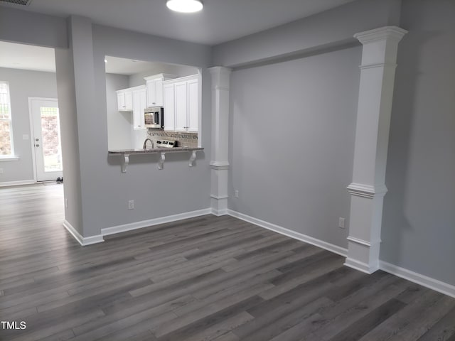 408 Timpson Ave, Durham, NC 27703 - kitchen with stainless steel microwave, white cabinets, dark wood finished floors, a breakfast bar area, and stone countertops