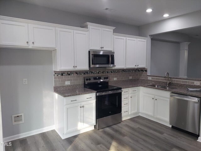 408 Timpson Ave, Durham, NC 27703 - kitchen featuring appliances with stainless steel finishes, white cabinetry, dark stone countertops, backsplash, and dark wood-type flooring
