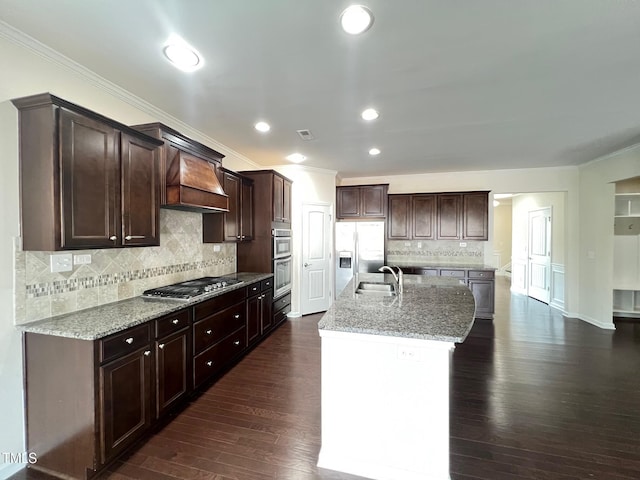 1521 Kythira Dr, Apex, NC 27502 - kitchen with stainless steel appliances, crown molding, a center island with sink, tasteful backsplash, and dark brown cabinetry