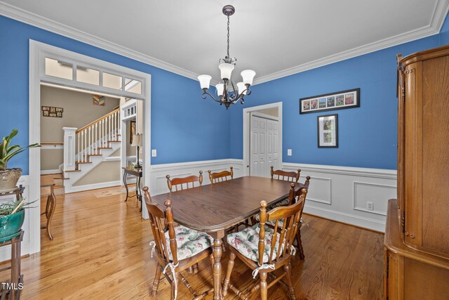 2424 Village Of Wakefield Dr, Zebulon, NC 27597 - dining room featuring a chandelier, stairs, ornamental molding, light wood-style floors, and wainscoting