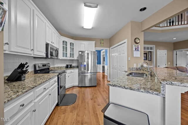 2424 Village Of Wakefield Dr, Zebulon, NC 27597 - kitchen featuring appliances with stainless steel finishes, light wood-style floors, white cabinets, glass insert cabinets, and recessed lighting