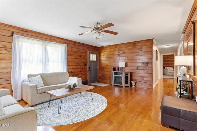 7323 Powell Hooks Rd, Lucama, NC 27851 - living area featuring light wood-style floors, ceiling fan, and wooden walls