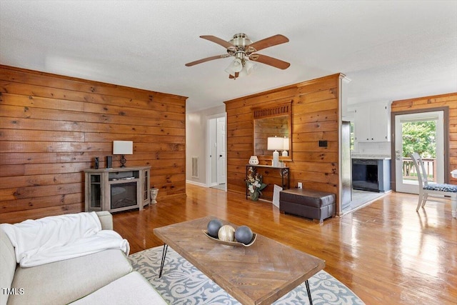 7323 Powell Hooks Rd, Lucama, NC 27851 - living room with a fireplace, wooden walls, light wood-style flooring, and ceiling fan