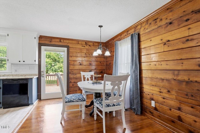 7323 Powell Hooks Rd, Lucama, NC 27851 - dining area with a chandelier, plenty of natural light, wooden walls, a textured ceiling, and light wood-style flooring