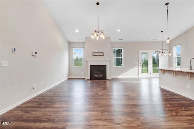 56 E Copenhaver Dr, Clayton, NC 27527 - unfurnished living room with a chandelier, plenty of natural light, dark wood-style floors, a fireplace with flush hearth, and recessed lighting