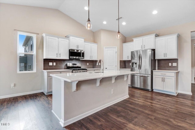 56 E Copenhaver Dr, Clayton, NC 27527 - kitchen featuring appliances with stainless steel finishes, vaulted ceiling, light countertops, white cabinetry, and tasteful backsplash
