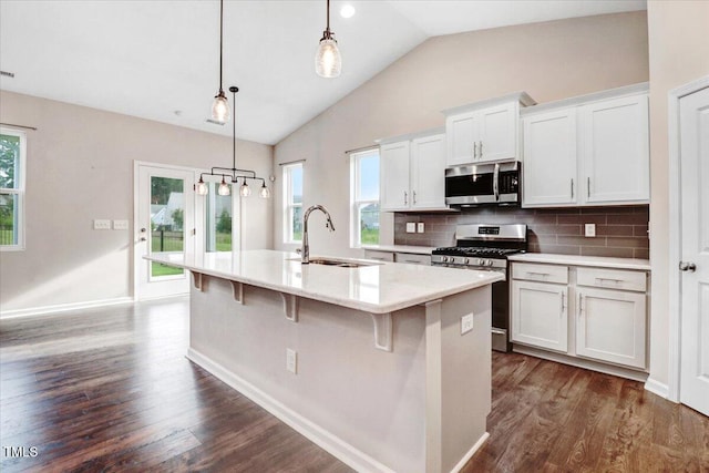 56 E Copenhaver Dr, Clayton, NC 27527 - kitchen featuring appliances with stainless steel finishes, an island with sink, dark wood-style floors, vaulted ceiling, and light countertops