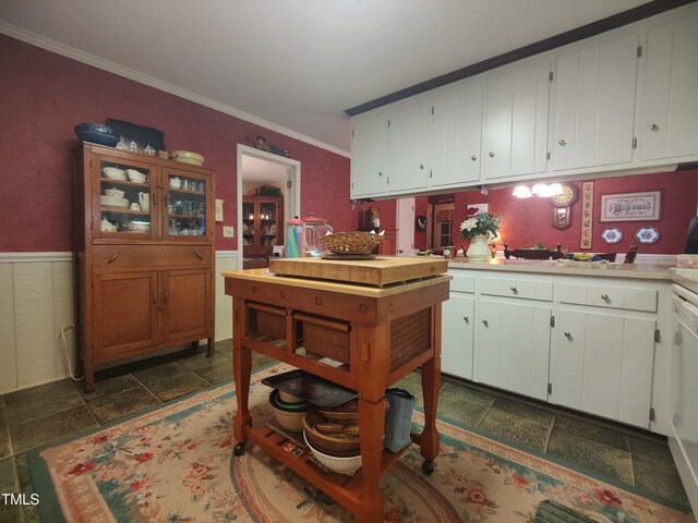 6517 Whitted Rd, Fuquay Varina, NC 27526 - kitchen with crown molding, stone tile floors, light countertops, white cabinetry, and a wainscoted wall