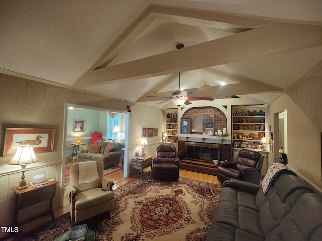 6517 Whitted Rd, Fuquay Varina, NC 27526 - living room featuring wooden walls, wood finished floors, ceiling fan, a glass covered fireplace, and built in shelves
