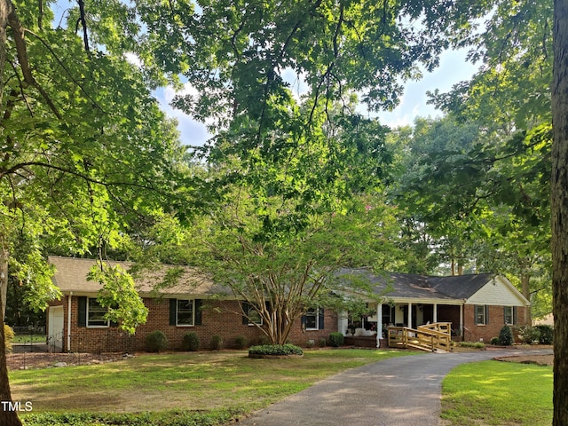 6517 Whitted Rd, Fuquay Varina, NC 27526 - ranch-style house featuring a porch, brick siding, a front lawn, and asphalt driveway