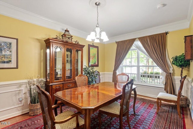 12212 Ashton Woods Ln, Raleigh, NC 27614 - dining area with a chandelier, ornamental molding, wood finished floors, wainscoting, and a decorative wall