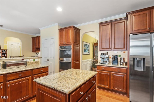 12212 Ashton Woods Ln, Raleigh, NC 27614 - kitchen featuring stainless steel appliances, arched walkways, ornamental molding, light stone counters, and a kitchen island