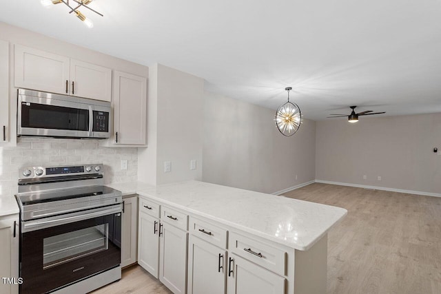 407 E Williams St, Angier, NC 27501 - kitchen with appliances with stainless steel finishes, a peninsula, light wood-style flooring, tasteful backsplash, and a ceiling fan