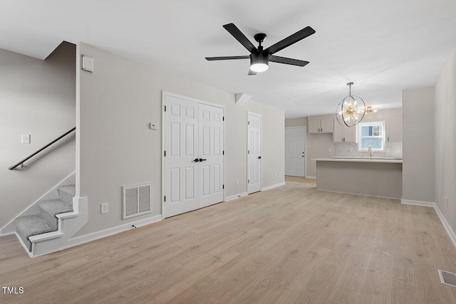 407 E Williams St, Angier, NC 27501 - unfurnished living room featuring light wood finished floors, a ceiling fan, stairs, and a chandelier