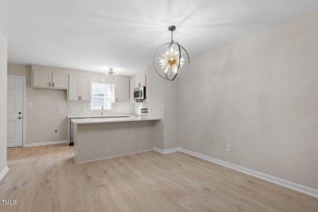 407 E Williams St, Angier, NC 27501 - kitchen with stainless steel microwave, a chandelier, light wood finished floors, and a peninsula