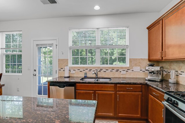 118 Tweedbank Ct, Fuquay Varina, NC 27526 - kitchen with stainless steel appliances, dark stone counters, backsplash, brown cabinetry, and recessed lighting