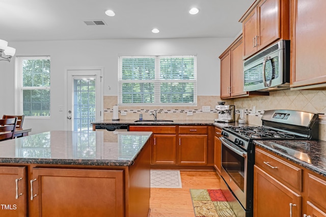118 Tweedbank Ct, Fuquay Varina, NC 27526 - kitchen with appliances with stainless steel finishes, light wood finished floors, dark stone countertops, a center island, and brown cabinets