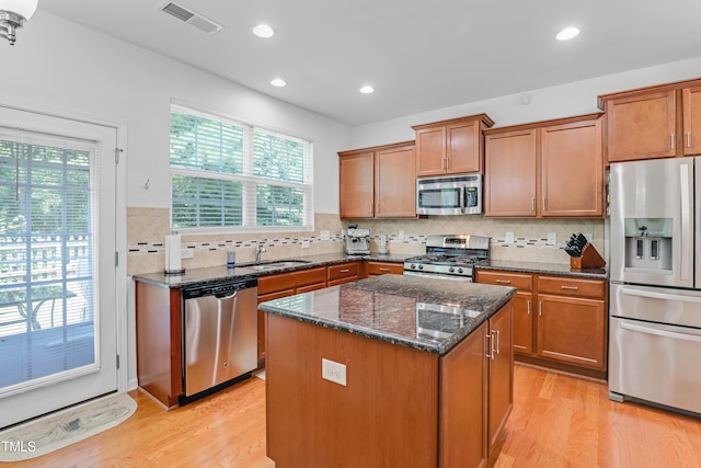 118 Tweedbank Ct, Fuquay Varina, NC 27526 - kitchen featuring appliances with stainless steel finishes, light wood-type flooring, recessed lighting, brown cabinetry, and dark stone counters
