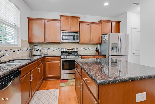 118 Tweedbank Ct, Fuquay Varina, NC 27526 - kitchen with appliances with stainless steel finishes, light wood finished floors, brown cabinets, a kitchen island, and recessed lighting
