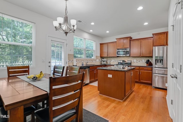 118 Tweedbank Ct, Fuquay Varina, NC 27526 - kitchen with appliances with stainless steel finishes, a chandelier, a kitchen island, light wood-type flooring, and tasteful backsplash