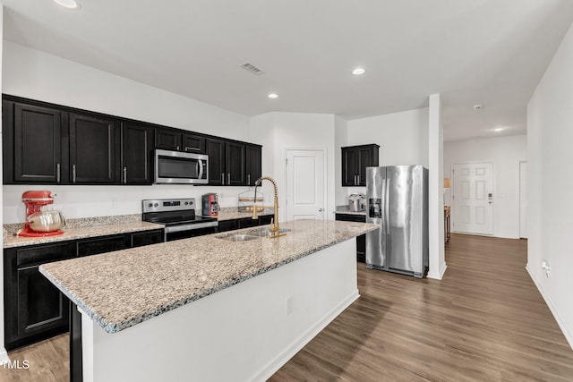 133 Ogden Pond Pl, Zebulon, NC 27597 - kitchen featuring appliances with stainless steel finishes, dark cabinets, recessed lighting, an island with sink, and light wood-style floors