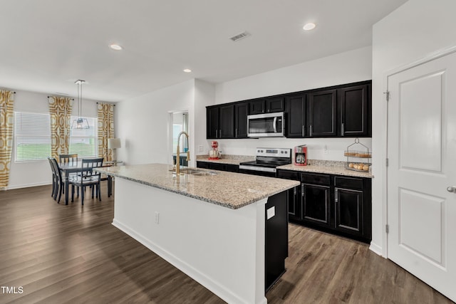 133 Ogden Pond Pl, Zebulon, NC 27597 - kitchen with appliances with stainless steel finishes, dark cabinets, an island with sink, wood finished floors, and recessed lighting