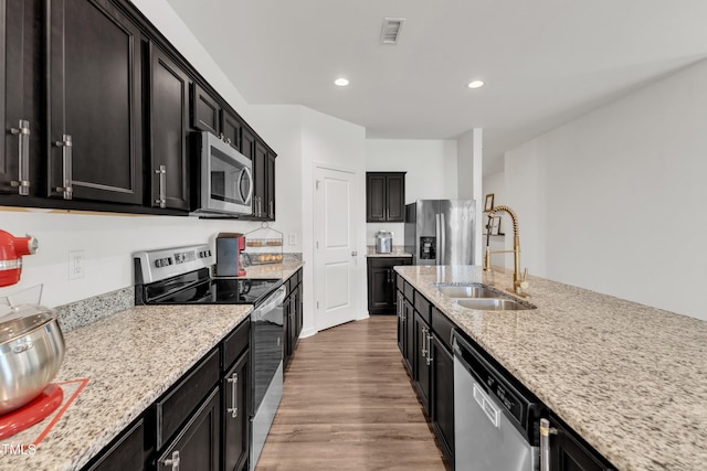 133 Ogden Pond Pl, Zebulon, NC 27597 - kitchen with appliances with stainless steel finishes, dark cabinetry, light wood-style flooring, light stone countertops, and recessed lighting