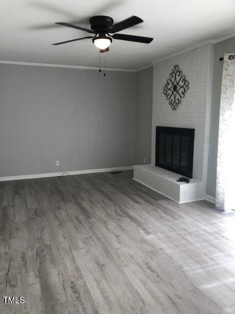 5018 Gatewood Dr, Durham, NC 27712 - unfurnished living room featuring ornamental molding, ceiling fan, wood finished floors, and a fireplace