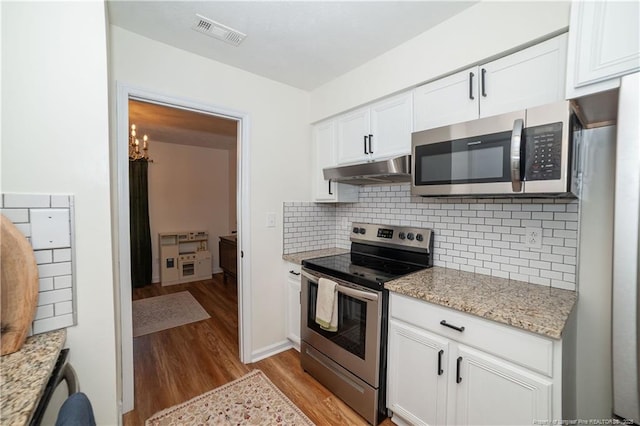 2517 Previs Rd, Fayetteville, NC 28306 - kitchen with stainless steel appliances, under cabinet range hood, light wood-style flooring, white cabinets, and tasteful backsplash