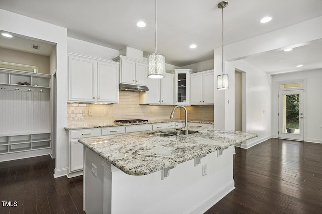 261 Begen St, Morrisville, NC 27560 - kitchen featuring under cabinet range hood, stainless steel gas cooktop, dark wood-type flooring, white cabinets, and decorative backsplash