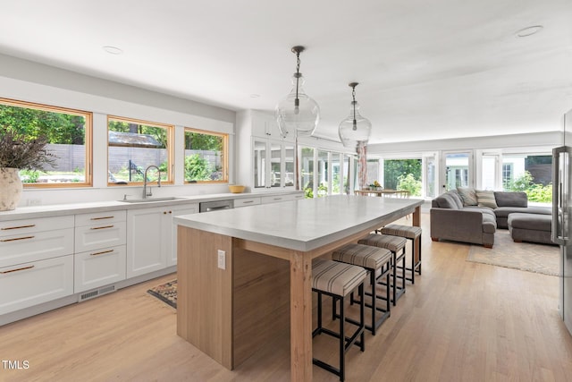 317 Reade Rd, Chapel Hill, NC 27516 - kitchen featuring a kitchen island, a kitchen bar, white cabinets, light wood finished floors, and light countertops