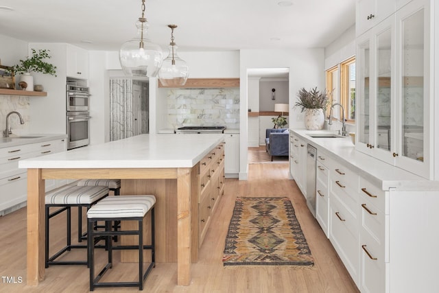 317 Reade Rd, Chapel Hill, NC 27516 - kitchen featuring stainless steel double oven, open shelves, light wood-style floors, decorative backsplash, and a kitchen bar