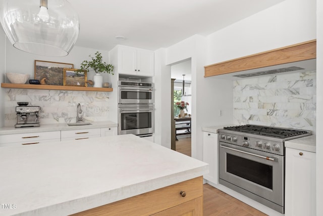 317 Reade Rd, Chapel Hill, NC 27516 - kitchen featuring appliances with stainless steel finishes, open shelves, backsplash, light countertops, and white cabinetry
